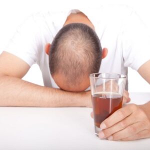 Depressed man with hair loss, bald head and drinking